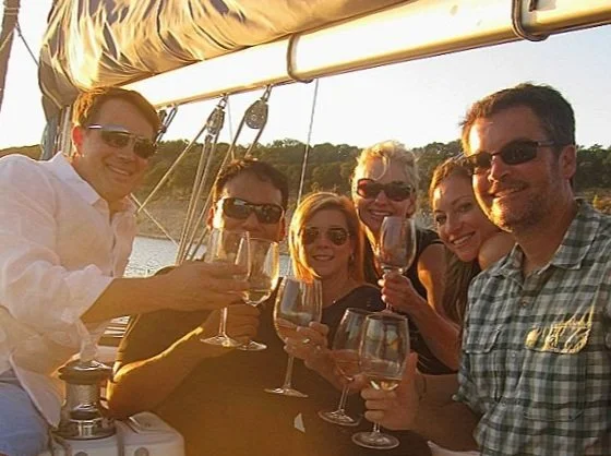 Friends toasting with wine on a Texas Sailing bachelorette charter at sunset